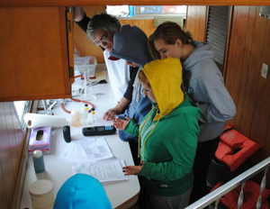 Students below deck on the Boat of Knowledge testing water quality parameters.