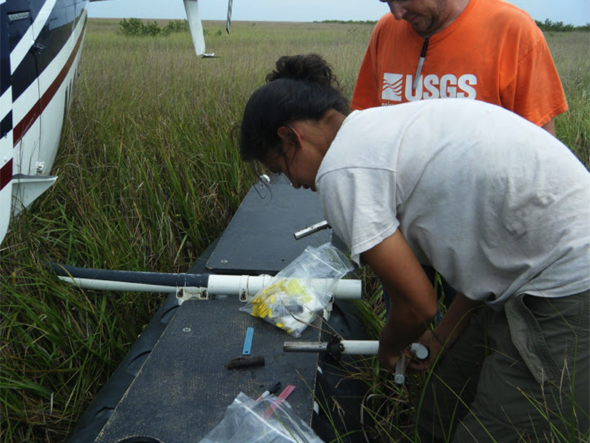 Khan and a U.S. Geological Survey collaborator measure a sediment sample from the wetland.