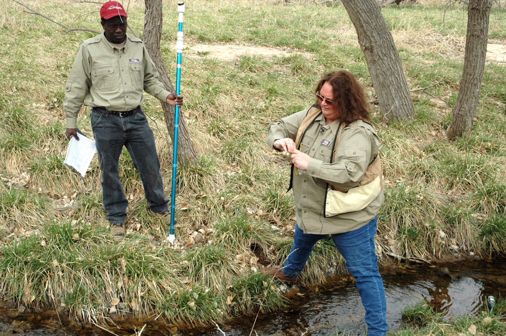 Phyllis Dyer takes a sample from Buck Creek as fellow associate, Partson Muvumba, looks on (Credit: Texas A&M AgriLife Research, Kay Ledbetter)