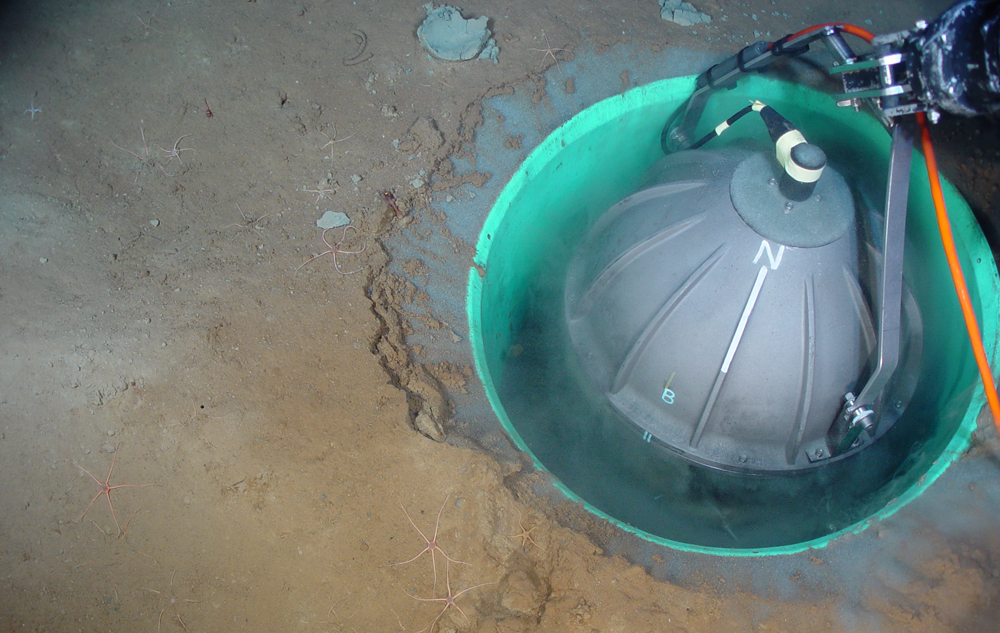 A Guralp broadband seismometer in a housing developed by the Monterey Bay Aquarium Research Institute being placed into a hole in sediments on the seafloor near the Endeavor Segment of the Juan de Fuca Ridge (Credit: Deborah Kelley and William Wilcock, UW)
