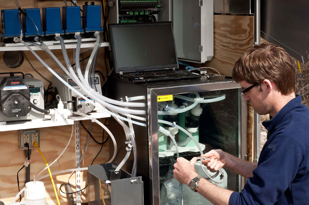 A scientist works in the sampler setup for a virus monitoring station (Credit: USGS)