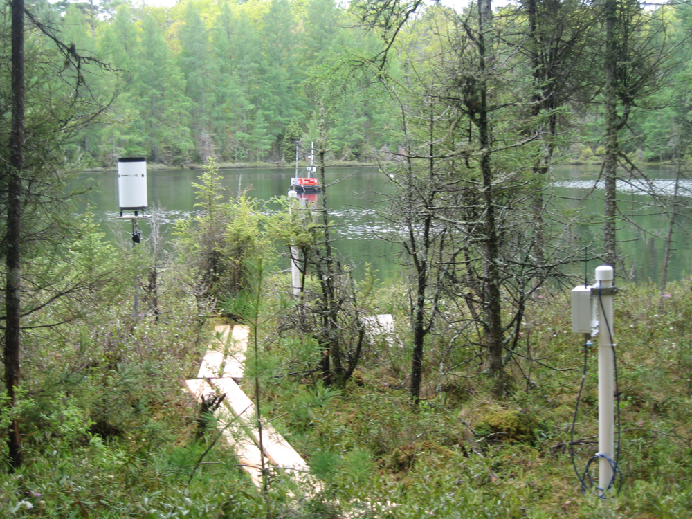An instrumented peatland monitoring well, the rain gauge and a GLEON buoy moored on the wetland pond 