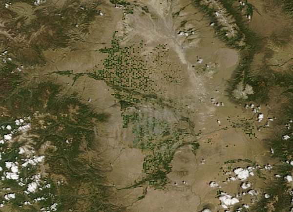 A satellite view of the San Luis Valley, with green circles of crops irrigated with groundwater pumped through center-pivot irrigation (Credit: NASA)