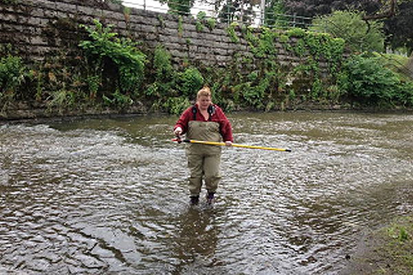Susan Little collects a water sample in Scajaquada Creek. (Credit: Chris Murawski / Buffalo Niagara Riverkeeper)