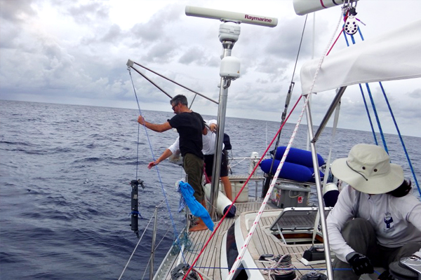 Profs. Grzymski and Cullen deploy a niskin bottle from the stern of S/Y Indigo V as crew Ruth McCance operates the winch.