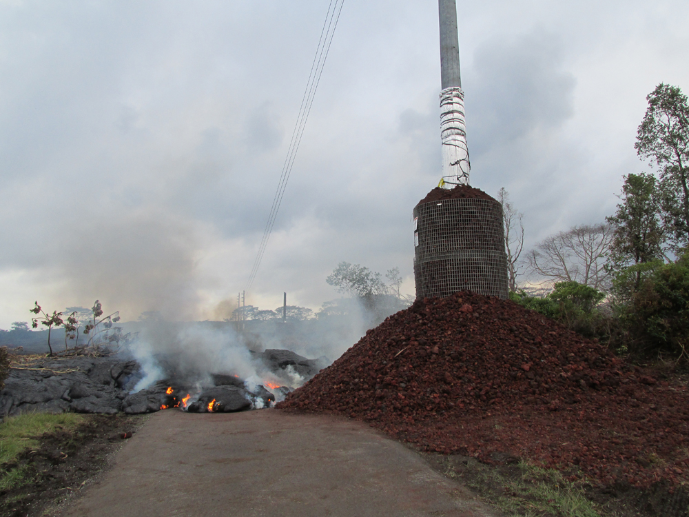 Nov. 9:  Lava approaches a utility pole protected by a cinder barrier. (Credit: USGS HVO)