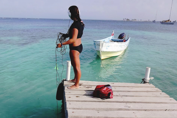 Madz Negro uses a hydrophone and digital recorder to capture sounds from and around Panamanian coral reefs. (Credit: Illinois Wesleyan University)