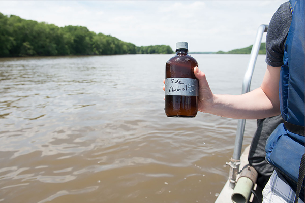 A LACMRERS student takes a water sample from a side channel of the Mississippi River. (Credit: University of Iowa)