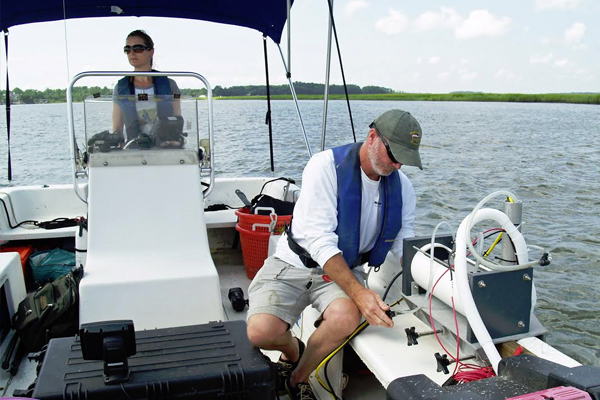 Researcher Mike Robinson prepares the salinity monitoring system for operation, while fellow researcher LeeAnn DeLeo drives the boat. (Credit: Skidaway Institute of Oceanography, U. Georgia)