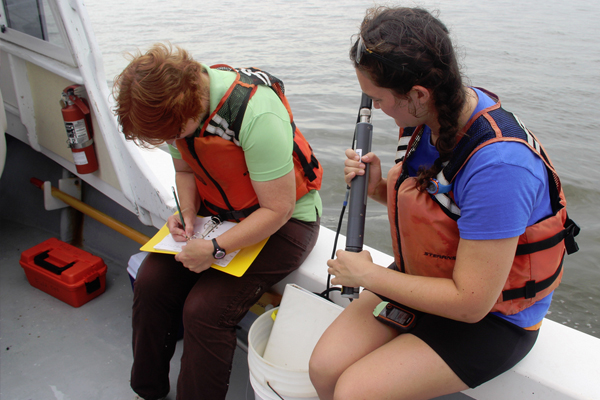 VIMS professor Kim Reece (left) and graduate student Sarah Pease measure water quality in the York River to explore potential links with bloom characteristics. (Credit: David Malmquist, Virginia Institute of Marine Science)