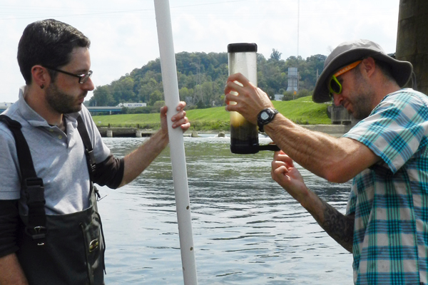 Daniel Hoffman (left) watches as Lee Slone secures the bottom of a sediment core with electrical tape on the downstream side of a dam on the Lower Great Miami River. (Credit: Nate Christopher / Fondriest Environmental)
