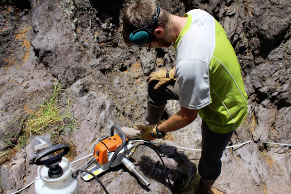 Lead author Brendan Murphy preparing to drill samples of bedrock from the streambed of Puanui Gulch on the dry side of Kohala Peninsula. (Credit: Kory Kirchner)