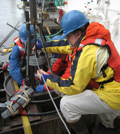 WHOI researcher Bruce Keafer, right, and colleagues prepare a corer to collect sediment samples from the seafloor. (Credit: Amy Lloyd-Rippe)