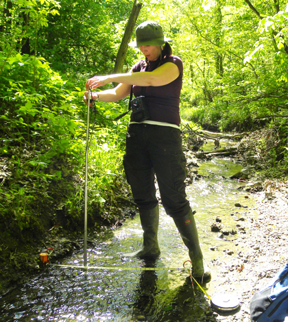 Michaeleen Gerken Golay measures stream flow in a forested headwater stream