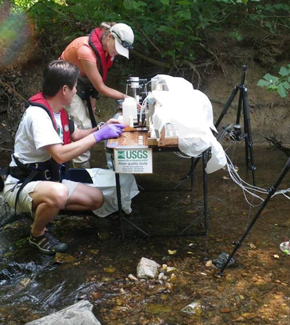 U.S. Geological Survey scientists sample water and sediment in Accotink Creek near Ranger Road in the City of Fairfax, Va. (Credit: Jud Harvey)