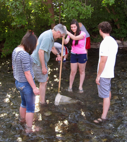 Stream Team volunteer Pat Costello teaches students with Big Sky Youth Empowerment to collect macroinvertebrates on Bozeman Creek. (Credit: Katherine Boyk)