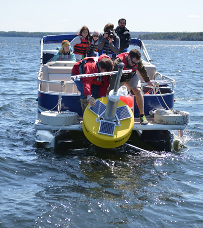 A crew launches "Goldie," the Great Pond data buoy (Credit: Colby College)