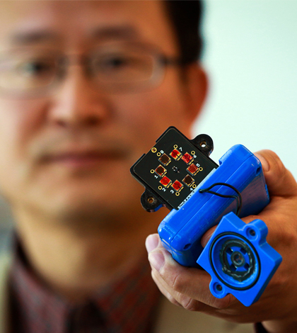 Professor Ling Zang holds a prototype detector. (Credit: Dan Hixon)
