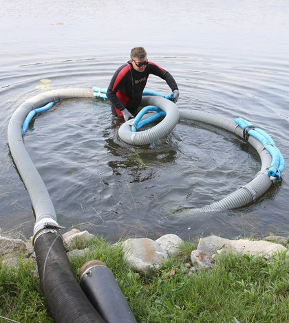 Jon Bunn prepares a floating suction hose to vacuum algae from the bay. (Credit: C.T. Kruger)
