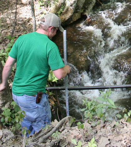 Tyler Evans measuring depth at a custom tag antenna site for estimating discharge at Mitchell Brook, Whately, Massachusetts. (Credit: U.S. Geological Survey)