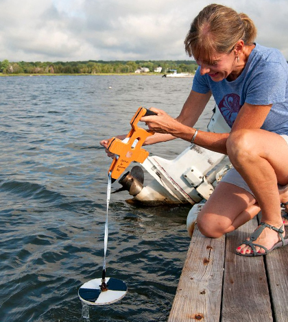 Volunteer Michelle Helms measures water clarity using a Secchi disk in Apponagansett Bay. (Credit: Buzzards Bay Coalition)