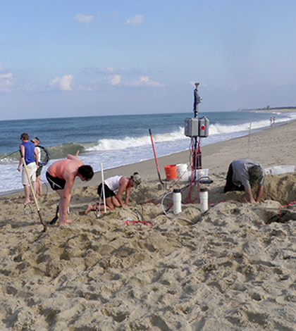 Researchers install instrument arrays in the beach at Herring Point, Cape Henlopen. The instruments were buried in the unsaturated zone to monitor the movement of groundwater in response to waves running up and down the beach. (Credit: University of Delaware)