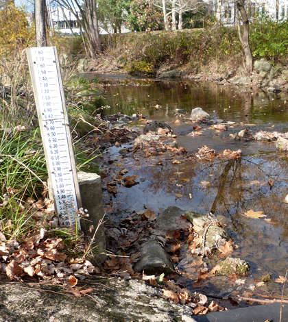 A staff gauge tracks Tiffin, Ohio’s Rock Creek’s water levels. Its water is pumped out for sampling through a pipe. (Credit: Daniel Kelly / Fondriest Environmental)
