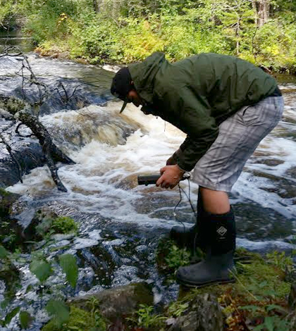 A field technician with the Penobscot Indian Nation uses a pH meter to take stream quality measurements. (Credit: Dan Kusnierz / Penobscot Indian Nation)