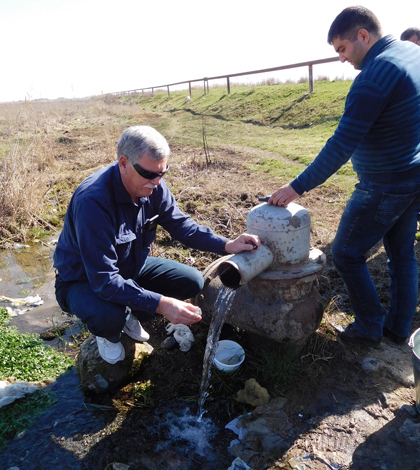 Mark Anderson, director of the USGS South Dakota Water Science Center, demonstrates how to collect a stable isotope sample from a flowing well near Sis, Armenia. (Credit: U.S. Geological Survey)