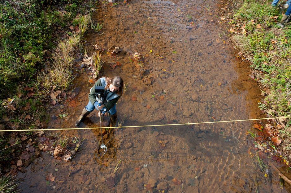 Jen Bowman, Ohio University, measures discharge in Hewett Fork an acid mine drainage impacted stream in the Raccoon Creek Watershed. The water is brown and orange due to acid mine drainage