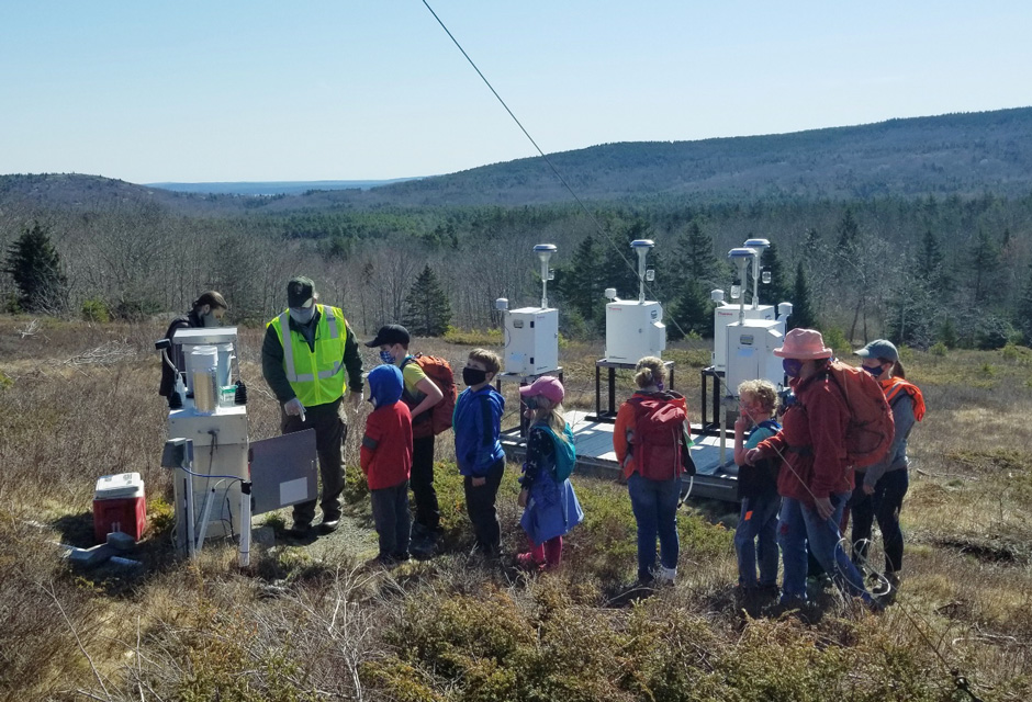 Acadia NP Biological Technician Jake Van Gorder and Air-Water Program Manager Bill Gawley demonstrate the operation of a precipitation sampler to a group of homeschoolers during their visit to the park’s air quality monitoring station.