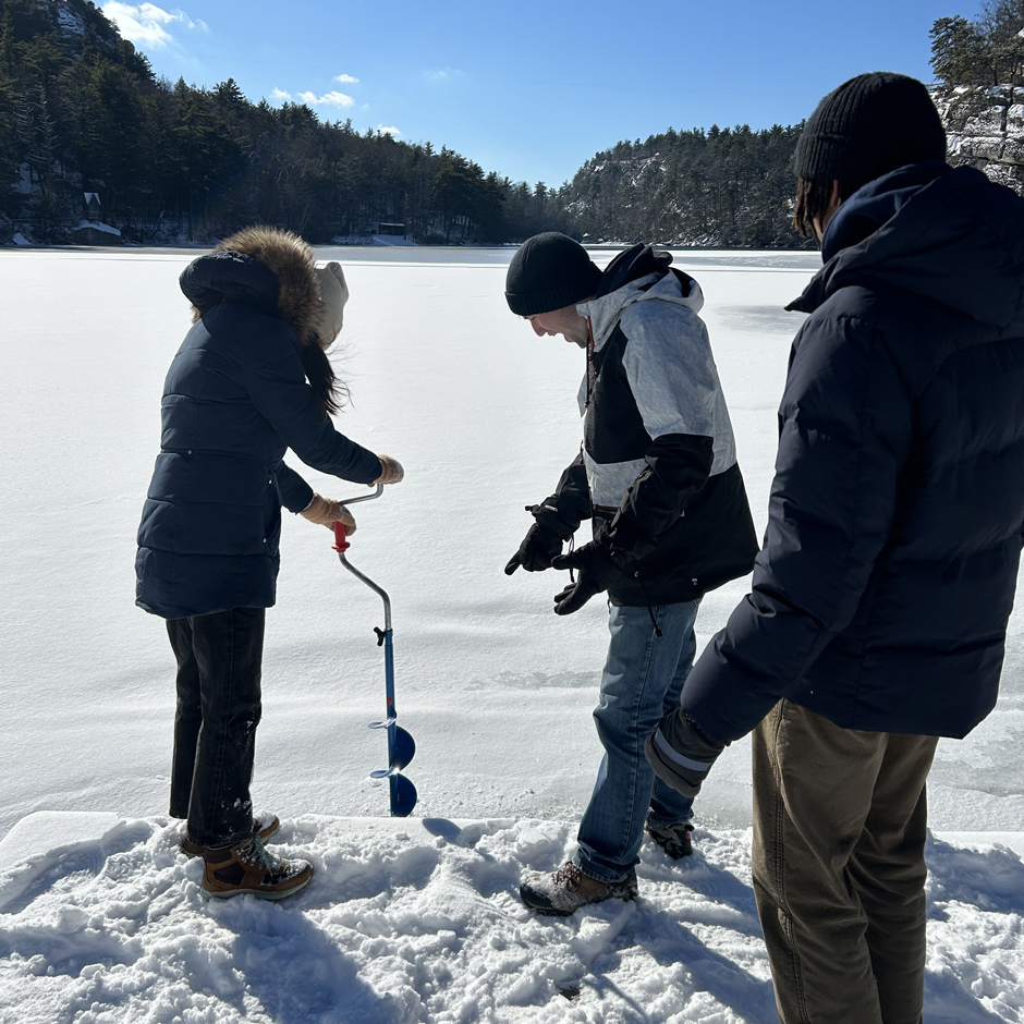 Delaney Long (Biology '24) drills a hole in the ice at Mohonk Lake with a hand ice auger. Kian Gallagher (Biology '24) and Dom Edwards (Biology '24) look on as they prepare to sample chemistry, biology, and physics of the lake under ice in winter conditions. 