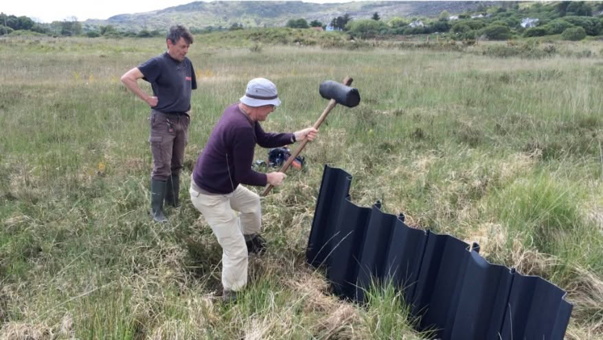 Two IPCC workers install plastic drain pilings.