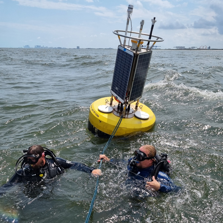 Scuba divers attaching the surface buoy to the bottom anchors using lines and chains.
