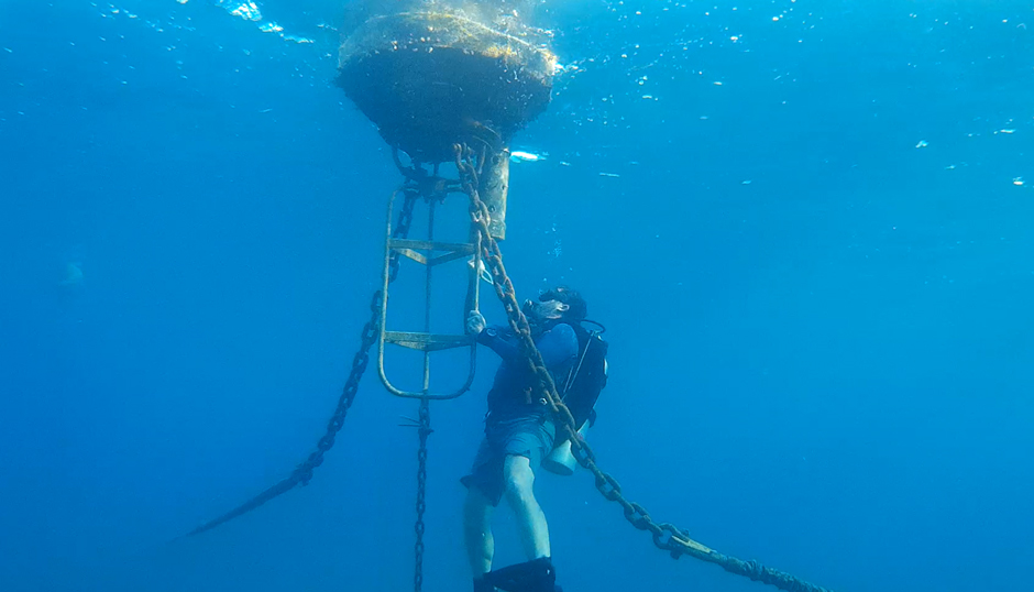 Divers servicing the surface buoy by cleaning the sensors to eliminate biofouling accumulation.