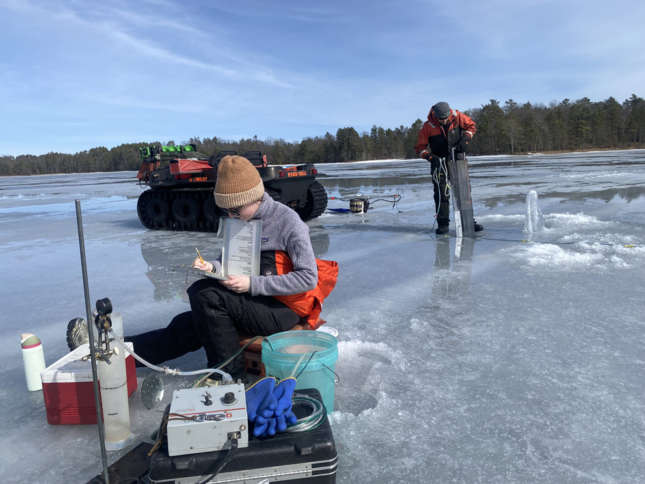 Trout Lake Research Station scientists sit on an ice covered lake and conduct water and ice measurement.