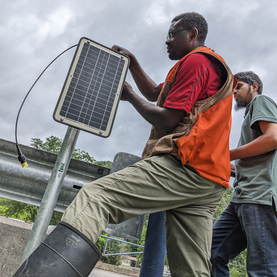 Franklin Kondum and Ridwan Nur, PhD students at UofL, install NexSens X3 datalogger and solar panel for a monitoring station on Cowan Creek, a headwater stream in Letcher County, KY.