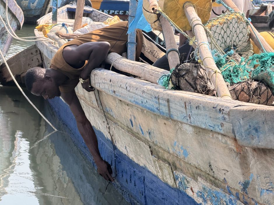 A fisher fixes the probe along the side of the hull.