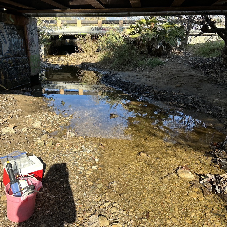 Sycamore Creek under a railroad bridge. This creek often runs dry in the summer months. In the bottom left, you can see the Creeks Division staff’s YSI ProDSS and cooler for storing bacteria samples.