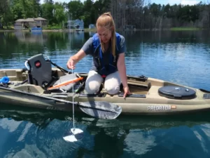 A volunteer lowers a Secchi disc to measure the water clarity of the lake.